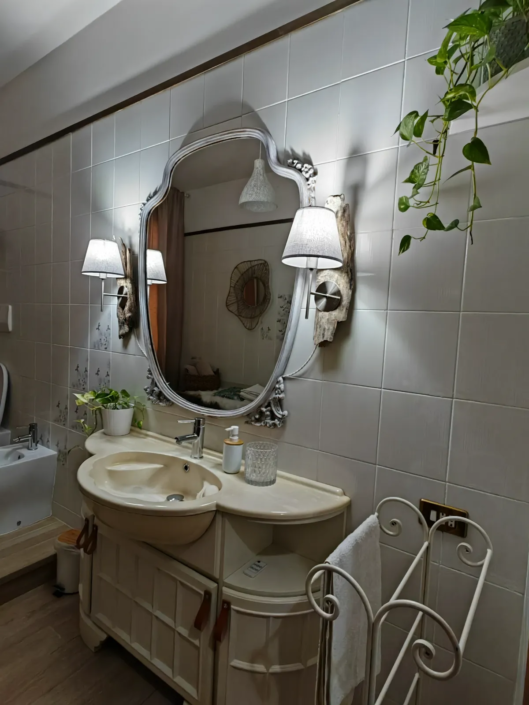 Lavabo con specchio ovale, applique e piante nel bagno, casa vacanze Verdeacquassisi ad Assisi