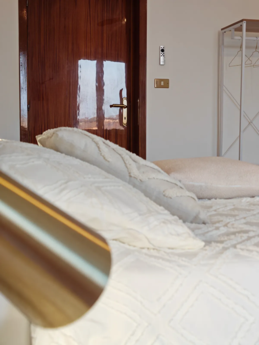 Letto matrimoniale con biancheria bianca e lampada da lettura, casa vacanze Verdeacquassisi ad Assisi