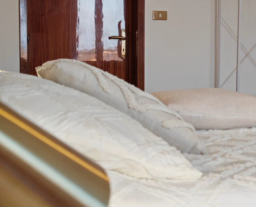 Letto matrimoniale con biancheria bianca e lampada da lettura, casa vacanze Verdeacquassisi ad Assisi