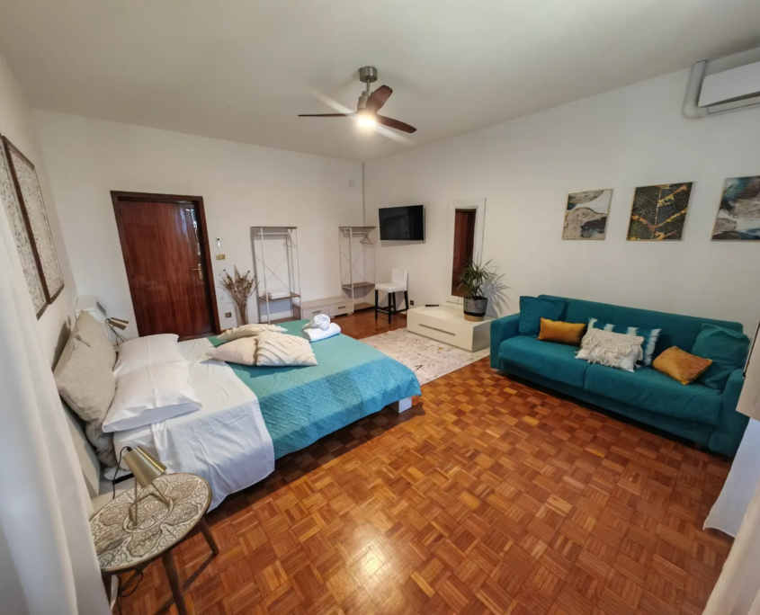 Camera LUCE, vista d'insieme con letto, divano verde acqua e parquet, casa vacanze Verdeacquassisi ad Assisi