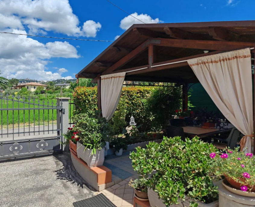 Gazebo con tende e piante nel giardino privato, casa vacanze Verdeacquassisi ad Assisi