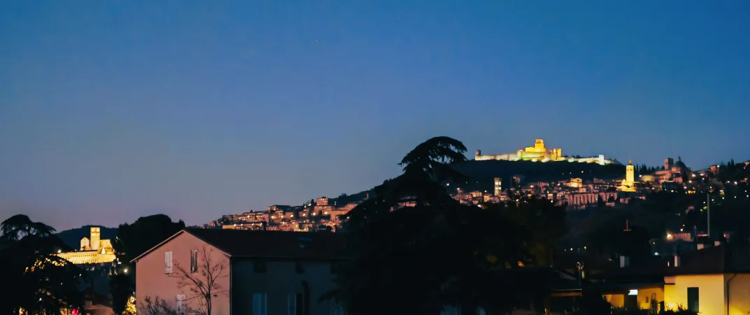 Vista notturna di Assisi illuminata da Verdeacquassisi