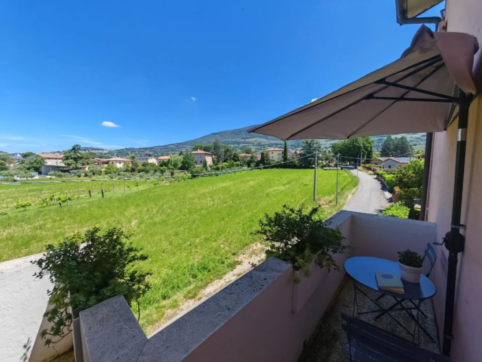 Terrazzino con ombrellone e vista sui campi verso le colline di Assisi, casa vacanze Verdeacquassisi ad Assisi