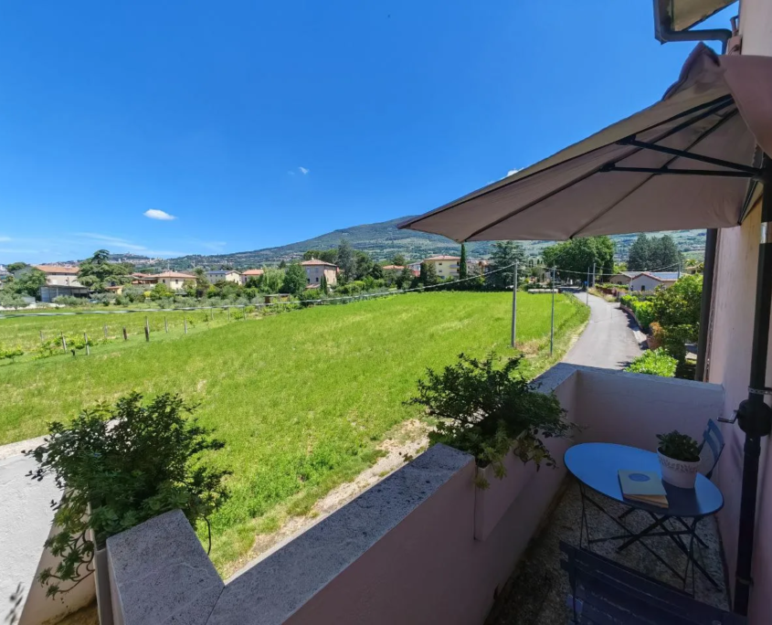 Terrazzino con ombrellone e vista sui campi verso le colline di Assisi, casa vacanze Verdeacquassisi ad Assisi